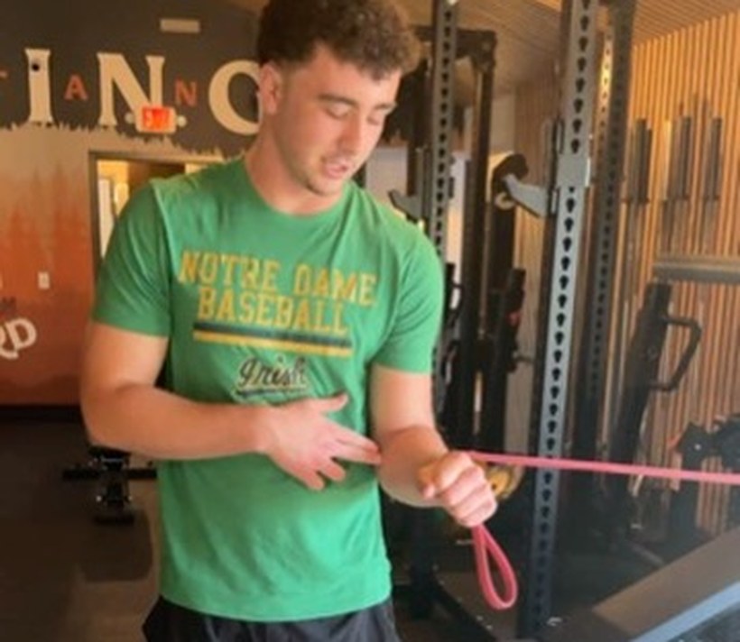 A baseball athlete working through a banded arm-care drill