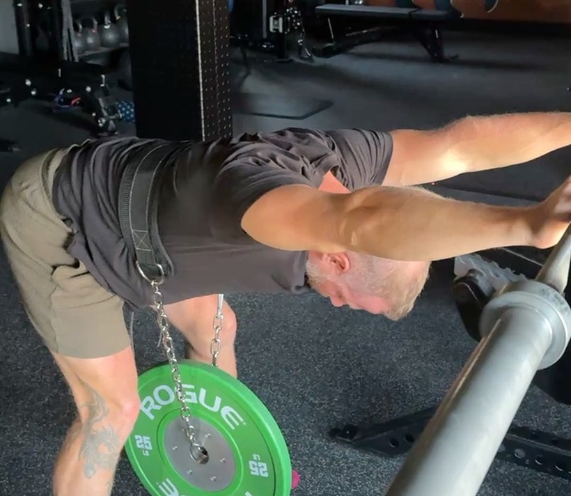 An athlete loading a hip hinge with a weighted belt