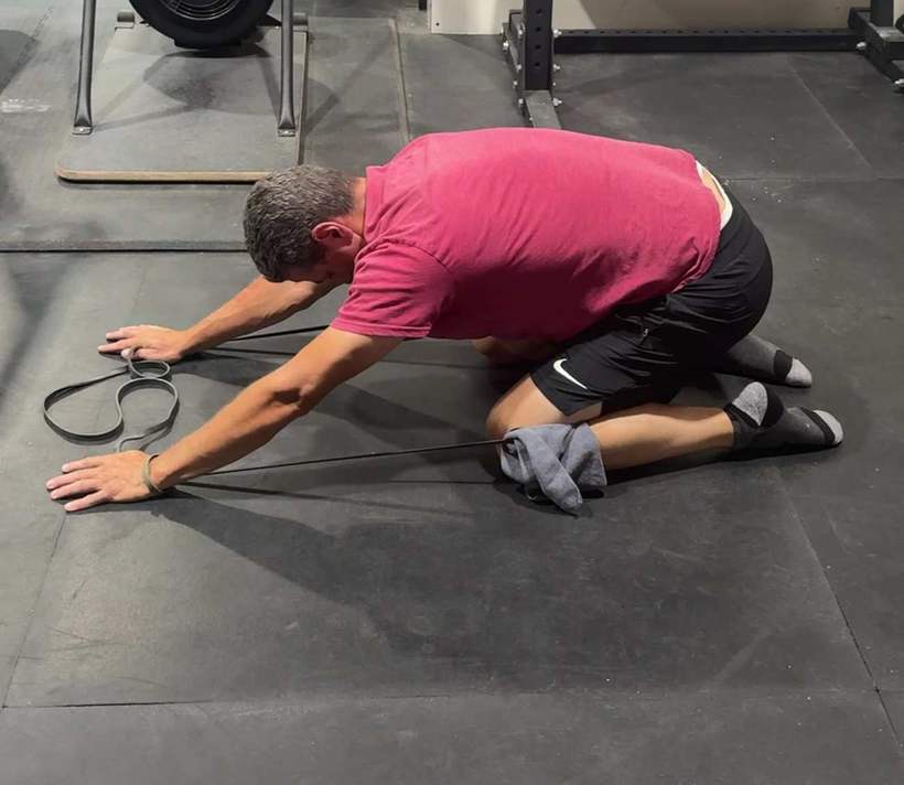 An athlete performing a banded plank drag